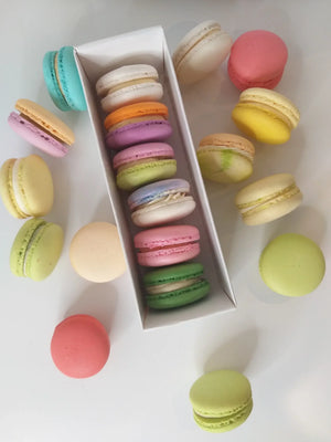 Colorful macarons in a white box with assorted flavors, arranged for display.